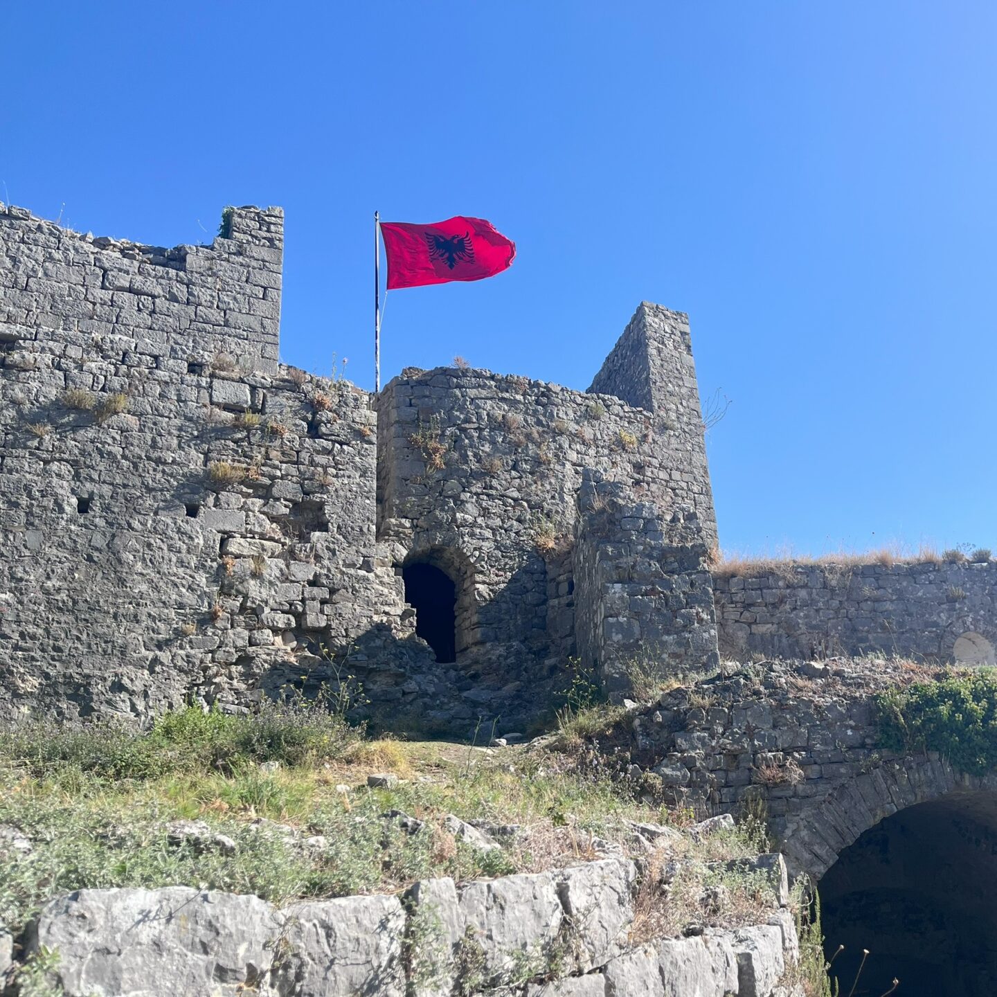 Black and red flag of Albania flying above the ruins of a castle