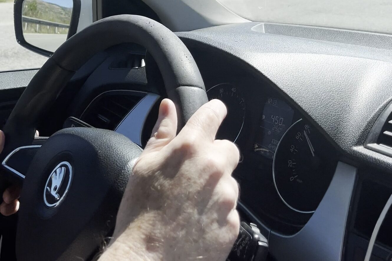 A man's hand on a steering wheel
